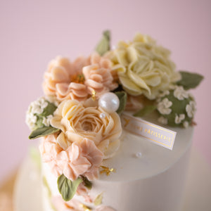 
                  
                    Load image into Gallery viewer, A close up on the top of the cake. It has many hand piped buttercream flowers in peach, pink and ivory. There are also handpiped green leaves around the flowers, resembling a bouquet. The flowers looks incredibly realistic.
                  
                