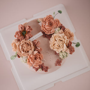 
                  
                    Load image into Gallery viewer, A light pink. buttercream base, with pink, beige and ivory buttercream flowers on top in a wreath style.
                  
                