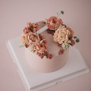 
                  
                    Load image into Gallery viewer, A light pink. buttercream base, with pink, beige and ivory buttercream flowers on top in a wreath style.
                  
                