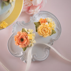 
                  
                    Load image into Gallery viewer, A close up on the matching cupcakes. They have hand piped coral, yellow and ivory buttercream flowers on top. There are some small white sugar pearls delicately scattered on top of the flowers, resembling dewdrops. 
                  
                