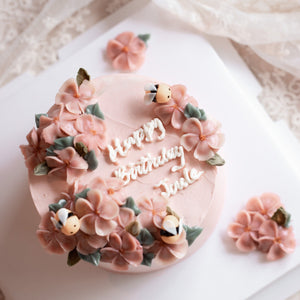 
                  
                    Load image into Gallery viewer, A light pink buttercream cake with pink buttercream flowers on top, decorated with little fondant bees. &amp;quot;Happy Birthday&amp;quot; is written in buttercream cursive in the middle of the cake.
                  
                