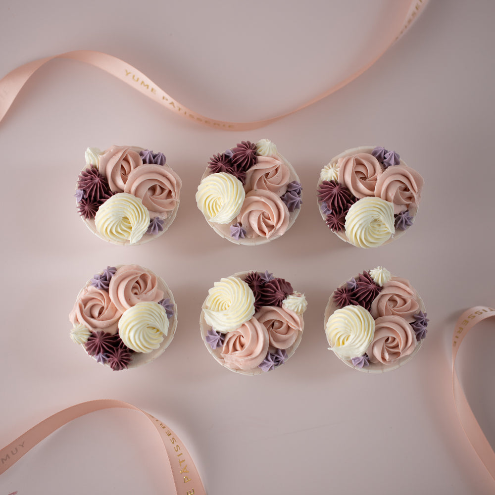 Cupcakes with white, light pink, light purple and burgundy buttercream swirls and kisses in different designs.