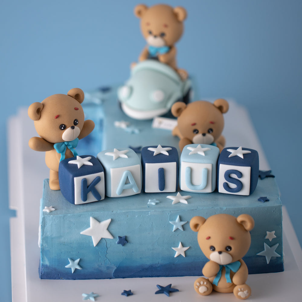 
                  
                    Load image into Gallery viewer, A close up on the base of the &amp;quot;one&amp;quot;. There are five fondant alphabet blocks, each containing an alphabet that spells the name &amp;quot;Kaius&amp;quot;. There are three fondant teddy bears around it. One of them is lying down, another has its arms up and looks surprised, and the last one is sitting on the cake board with a thoughtful expression on its face. 
                  
                